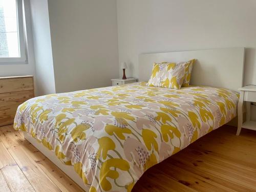 a bedroom with a bed with a yellow and white comforter at Casa do Padeiro - Sintra Country Cottages II in Montelavar