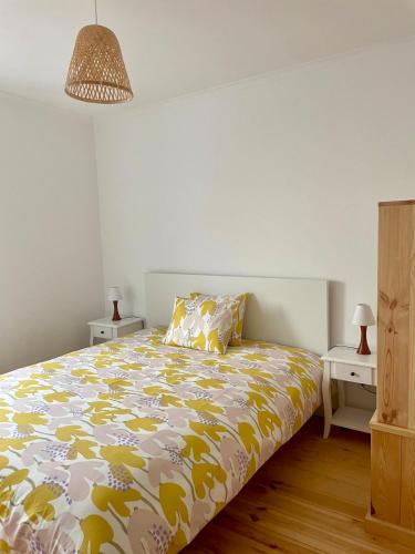 a bedroom with a bed with a yellow and white comforter at Casa do Padeiro - Sintra Country Cottages II in Montelavar