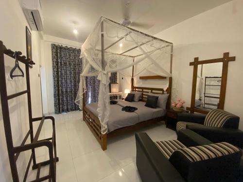 a bedroom with a canopy bed and a couch at Sigiri Holiday Bungalow in Sigiriya