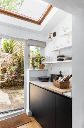 a kitchen with white walls and a skylight at Painter's Cottage in the Cotswolds in Woodchester