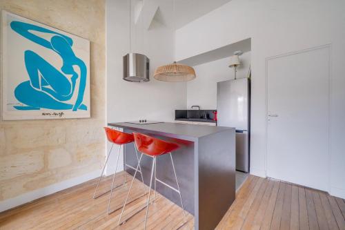 une cuisine avec comptoir et tabourets de bar rouge dans l'établissement Charming, modern flat with private parking, à Bordeaux