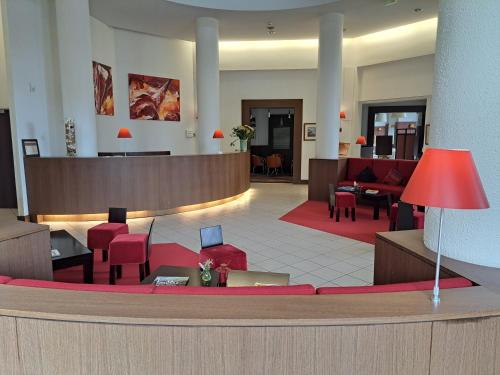 a lobby with a waiting area with red chairs at Hôtel Savoie Léman in Thonon-les-Bains