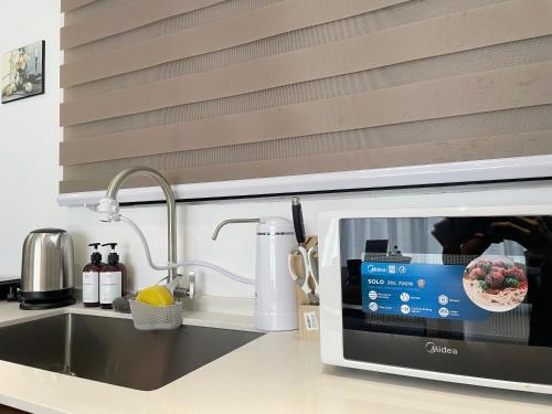 a microwave in a kitchen next to a sink at Le Petit Suite - 8 Pax Sea View Infinity Pool in George Town