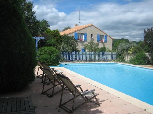une paire de chaises assises à côté de la piscine dans l'établissement Les pierres blanches, à Bonneuil-Matours