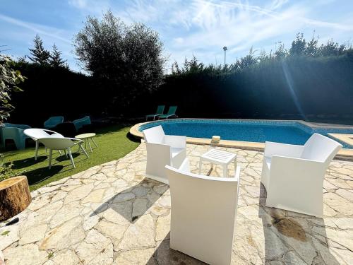 une terrasse avec des chaises blanches et une piscine dans l'établissement Villa Tropicannes Pool 5 bedrooms, au Cannet