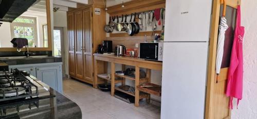 a kitchen with wooden cabinets and a white refrigerator at Maison Neuve, relaxing countryside home with pool in Chillac
