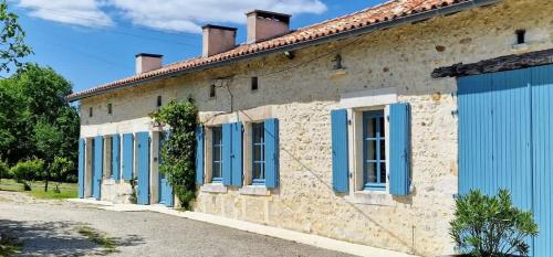 a stone house with blue shutters on a street at Maison Neuve, relaxing countryside home with pool in Chillac