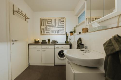La salle de bains blanche est pourvue d'un lavabo et d'un lave-linge. dans l'établissement 40qm Wohlfühl-Apartment im Grünen mit Sorglospaket, à Wuppertal