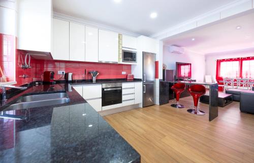 a kitchen with white cabinets and red walls at Full private 180sqm Villa - Terrace Jacuzzi - 200m Beach & Sea View in Albufeira