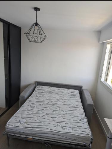 Ce lit se trouve dans un dortoir doté d'une lampe suspendue. dans l'établissement Appartement vue mer toute commodité, à La Seyne-sur-Mer