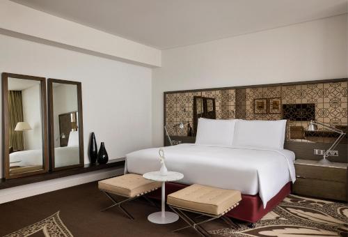 a bedroom with a large white bed and a bathroom at Conrad Abu Dhabi Etihad Towers in Abu Dhabi