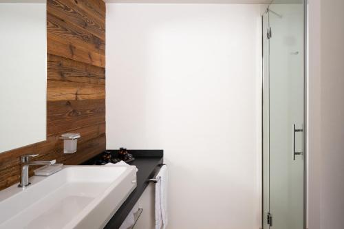 a bathroom with a white sink and a shower at Montana Lodge & Spa, by R Collection Hotels in La Thuile