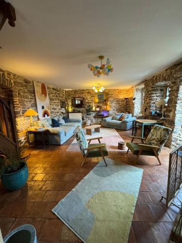 un salon avec des canapés et un mur en pierre dans l'établissement La Boussonie, Mas de caractère au pays des Vans, aux Vans