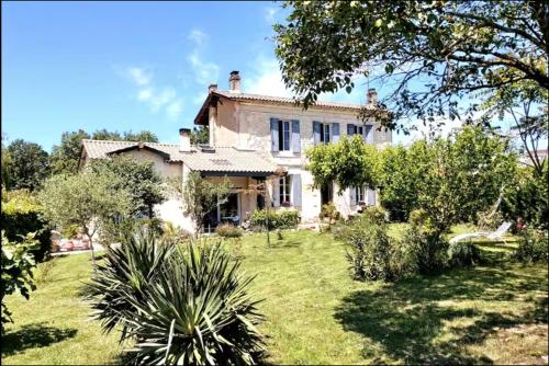 une grande maison blanche avec une cour ornée de plantes dans l'établissement Coeur des grands crus médoc, à Saint-Estèphe
