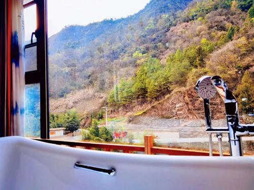 a bath tub with a view of a mountain at 淳安千岛湖乡庐怡陌民宿 in Thousand Island Lake