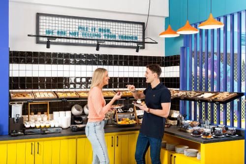 a man and a woman standing in a kitchen at Three Corners Hotel Anna in Budapest
