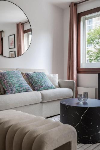 - un salon avec un canapé et un miroir rond dans l'établissement Spacious Apt 4PAX - Paris Courbevoie, à Courbevoie