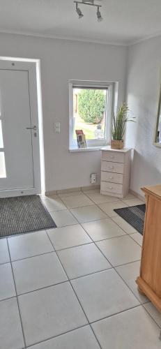 a room with a white tiled floor and a window at Ferienhaus "Unter den Linden" in Eggesin