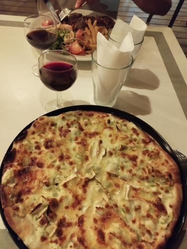 une pizza assise sur une table avec deux verres de vin dans l'établissement Camping Domaine de Senaud, à Albon