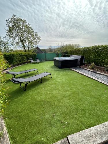 a backyard with two picnic tables and a green lawn at La ferme du paradis in Merris