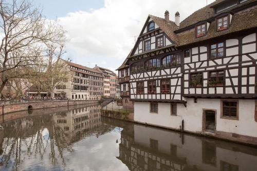 un bâtiment à côté d'une rivière dans une ville dans l'établissement Séjours & Affaires Strasbourg Kleber, à Strasbourg