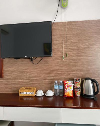 a television on a wall above a table with snacks at Flora Quy Nhon Hotel in Quy Nhon