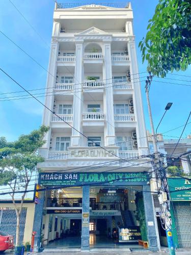 a large white building with a sign in front of it at Flora Quy Nhon Hotel in Quy Nhon