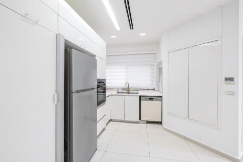 a kitchen with white cabinets and a refrigerator at sea view Vila-5BDR in Netanya
