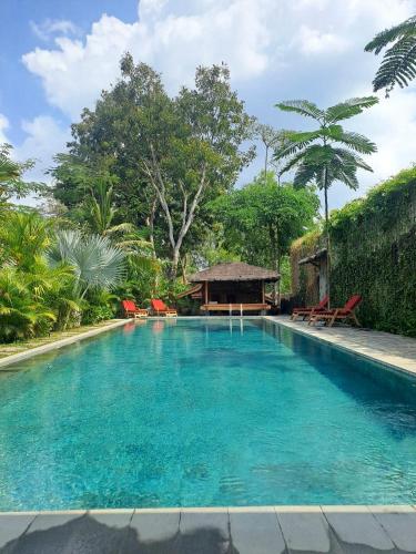 a large blue swimming pool with a gazebo at Imalee - Cottage in Yogyakarta