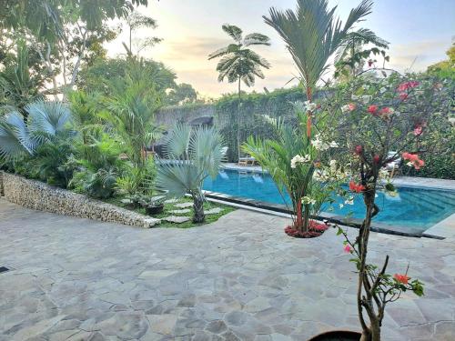 a resort with a pool and some trees and plants at Imalee - Cottage in Yogyakarta