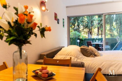 Cette chambre comprend un lit et une table avec un vase de fleurs. dans l'établissement Studio avec jardinet dans résidence avec piscine, à Sanary-sur-Mer