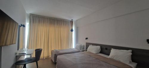 a bedroom with a bed and a chair and a window at Navarria Blue Hotel in Limassol
