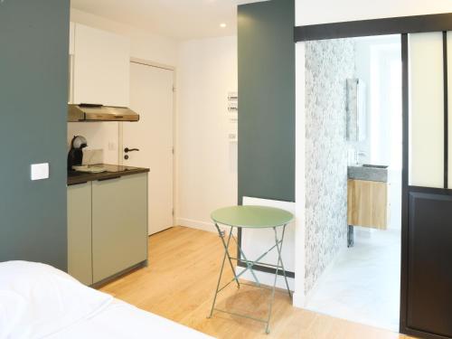 Cette chambre comprend un lit, une table et une cuisine. dans l'établissement Le Cocon studio, cognac, à Cognac