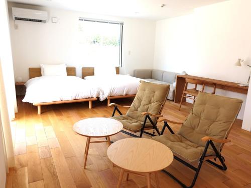 a room with two chairs and a bed and a table at takane no mori no cottage in Gotemba