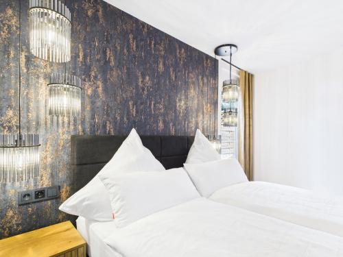 Un dormitorio con dos camas blancas y una pared con lámparas de araña. en Hochwertige Ferienwohnung in Seenähe mit Terrasse & Vollausstattung, en Uhldingen-Mühlhofen