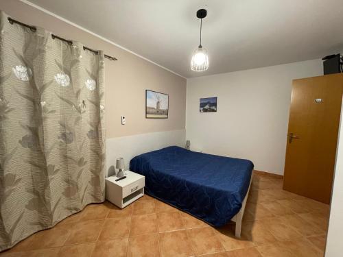 a small bedroom with a blue bed and a window at Rosa Di Makari in Macari