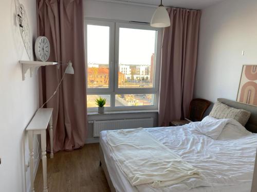 a bedroom with a bed and a large window at Przytulne mieszkanie na krótki pobyt, spacerem na starówkę in Toruń