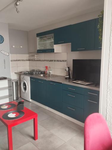 une cuisine avec des armoires bleues et une table rouge dans l'établissement Superbe appartement avec magnifique vue., au Barcarès