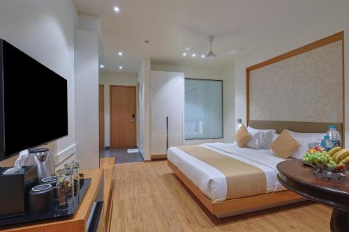 a bedroom with a large bed and a flat screen tv at HOTEL SERA, Vadodara in Vadodara