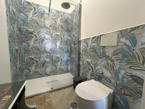 a bathroom with a toilet and a blue and green wallpaper at Casa Vacanze Mary Jane House in Fiumicino