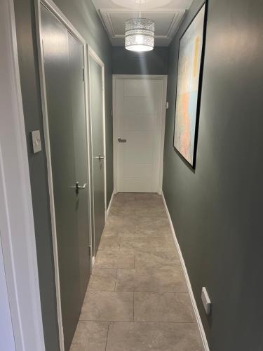 a hallway with a white door and a tile floor at Ballymacdoe Cottage Cushendall in Cushendall