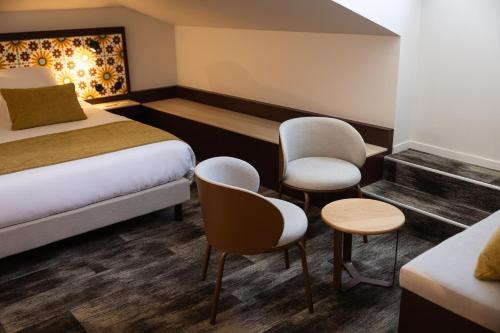 a hotel room with a bed and two chairs at Le Saint-Nicolas in La Rochelle