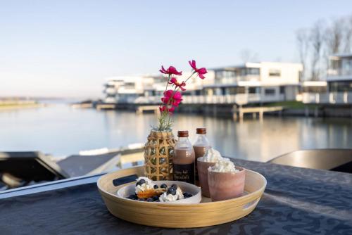 a tray of food on a table with drinks and flowers at Hello Zeeland - Water Villa's Veerse Wende - with dog in Arnemuiden