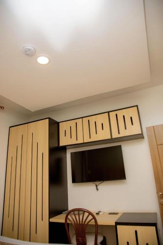 a kitchen with wooden cabinets and a desk with a tv at Saphir Boutique Hotel in Kigali