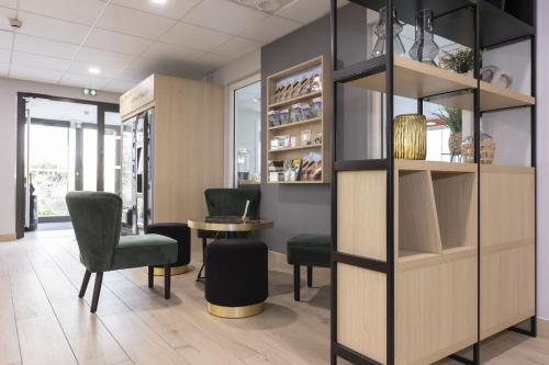 a waiting room with green chairs and a table at Appart Hotel Odalys City Colmar La Rose d'Argent in Colmar