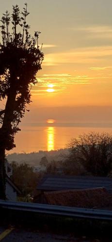 a sunset with the sun setting over the water at Le BéliMont Panorama in Belmont-sur-Lausanne