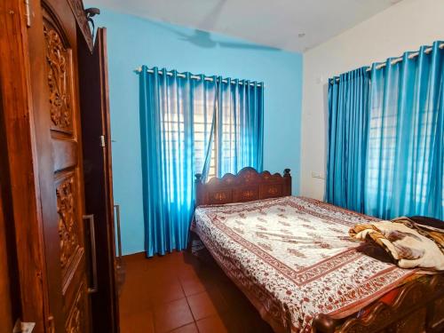 a bedroom with a bed with blue walls and blue curtains at Krishnalayam Heritage Villa in Elimala