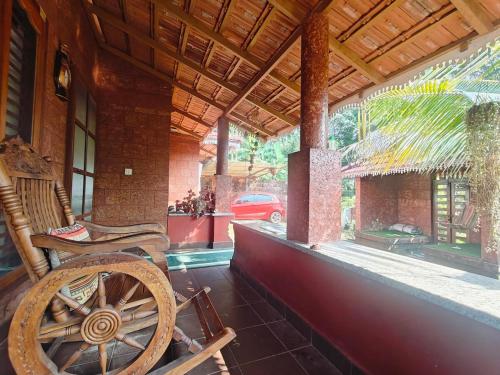 a porch of a house with a wooden wheel at Krishnalayam Heritage Villa in Elimala
