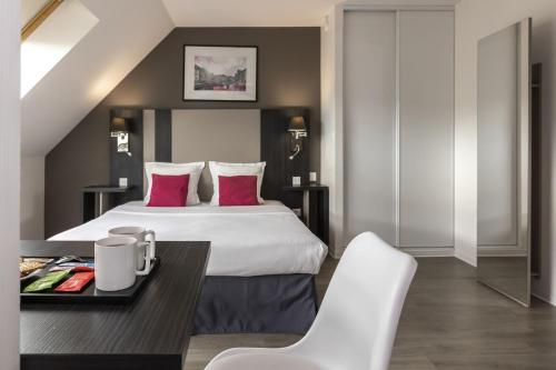a hotel room with a bed and a table and chairs at Appart Hotel Odalys City Colmar La Rose d'Argent in Colmar