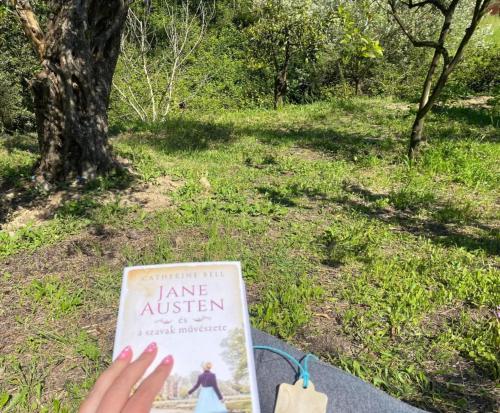 a person is reading a book in a park at Villa Cottage Eleni in Velonádes